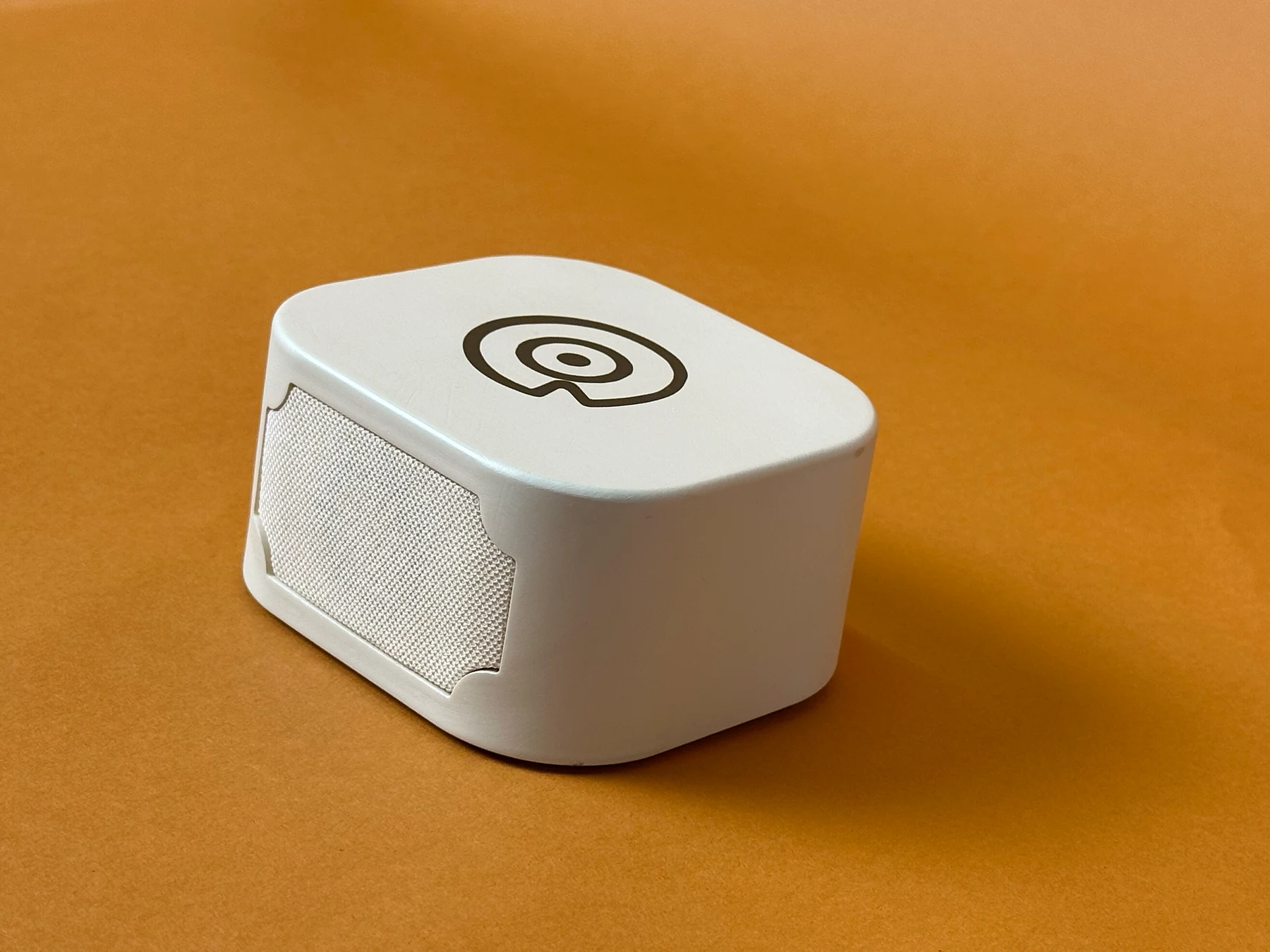 Three-quarter view of cream Story Dock, showing its top tap mark and woven speaker fabric